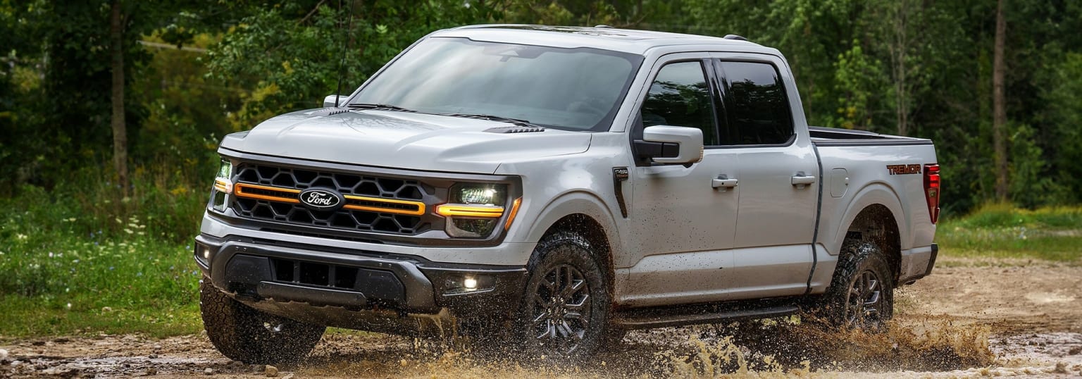 An off-road pickup truck in a muddy, forested environment, kicking up dirt and debris with its bold, aggressive design.