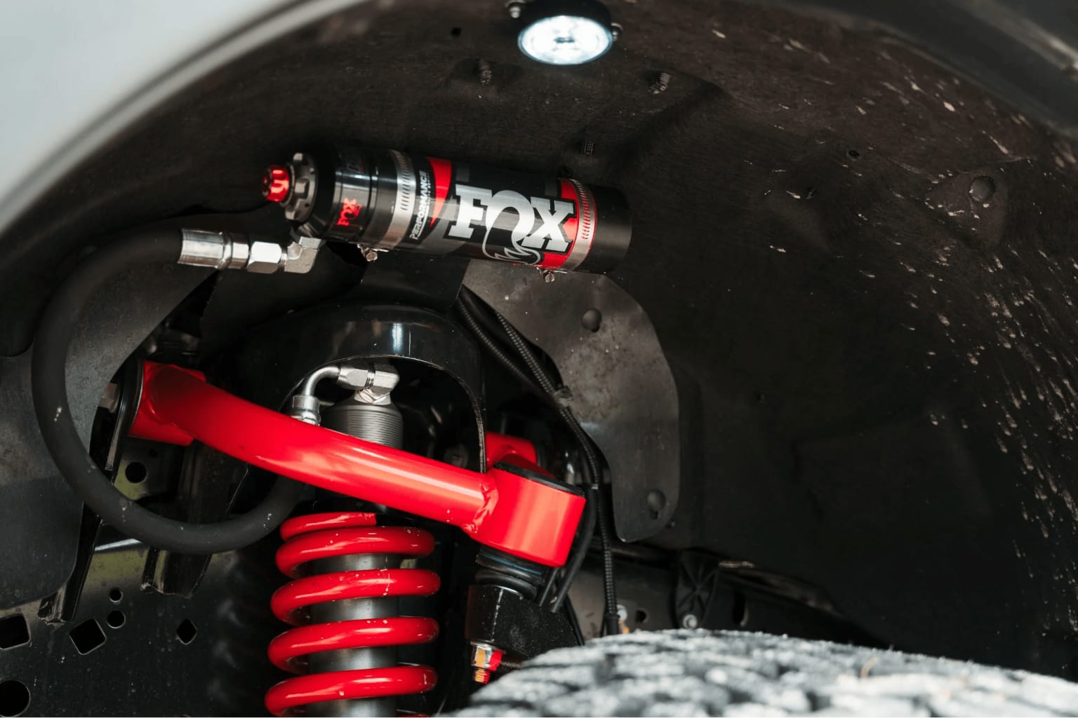 Close-up view of a red shock absorber or suspension component, mounted within a dark, textured background