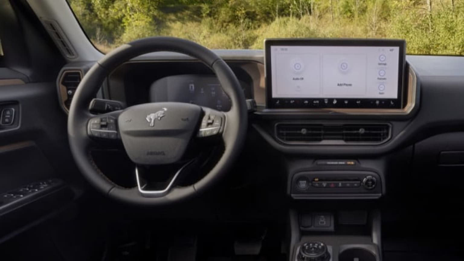 Dashboard of a modern car with a large touchscreen display and steering wheel, with a blurred outdoor scene in the background.