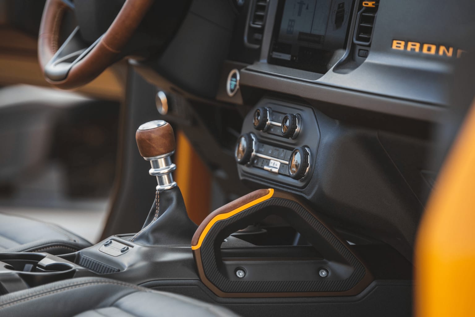 a close up of a car dashboard with a steering wheel and a dash board with a wooden dash stick