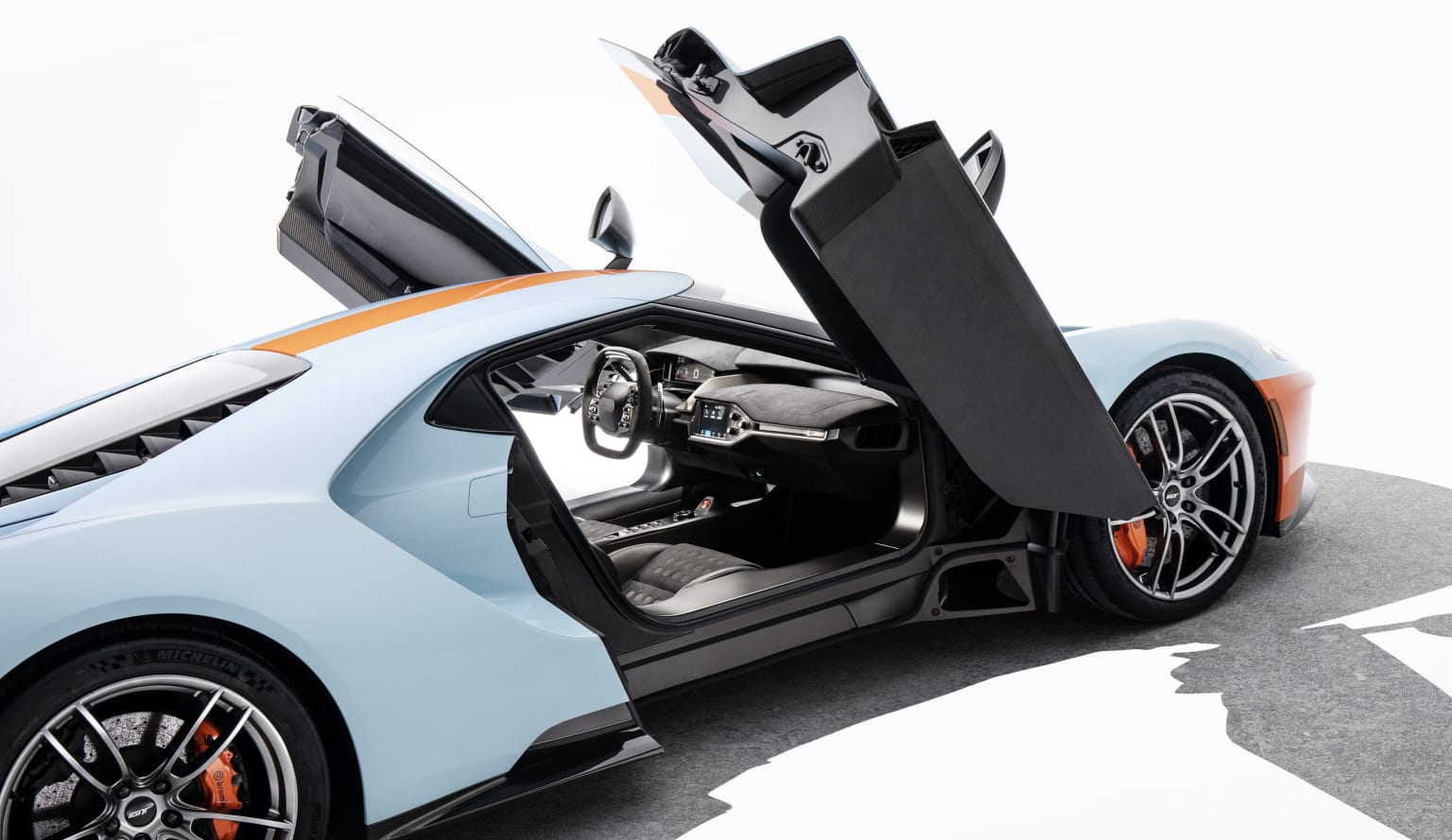 a blue and orange sports car with its doors open and the door open to show the inside of the car