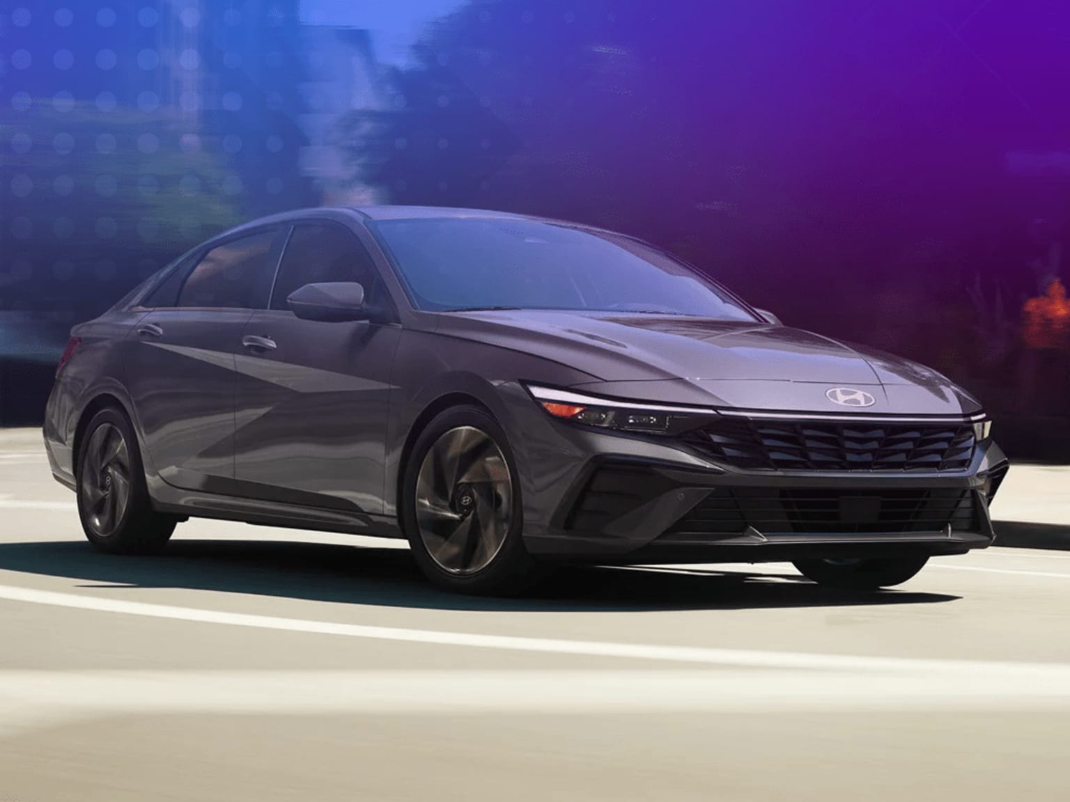 A sleek, dark-colored sedan is parked on a dimly lit street, with a blurred urban background visible in the distance.