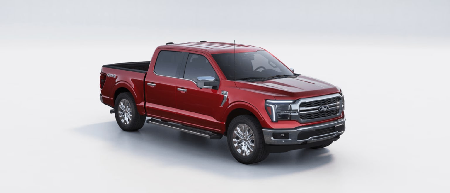 Red pickup truck with large grille and chrome accents against plain light-colored background.