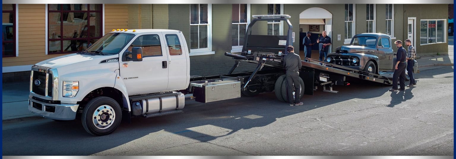 a flatbed tow truck with a flatbed trailer attached to the back of it's flatbed