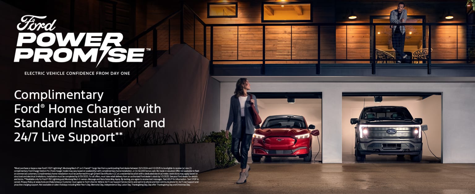 Interior of a well-lit garage with vehicles parked inside, including a red car and a larger vehicle, with a person standing in the foreground.