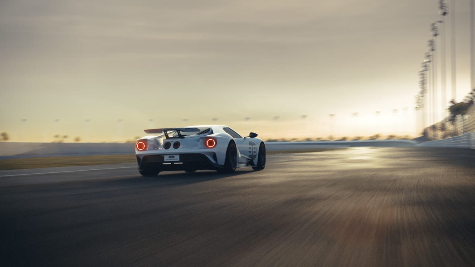 a white sports car driving down a race track at sunset or sunrise or sunset, with the sun shining on the rear end of the car