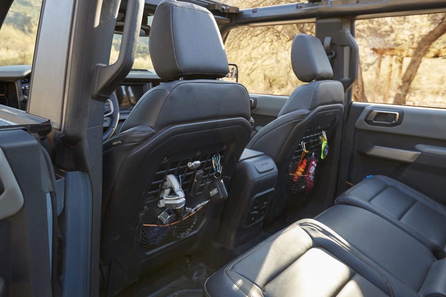 The image shows the interior of a vehicle, with the front seats and dashboard visible. The seats appear to be made of a dark material, and there are various storage compartments and accessories visible in the background.