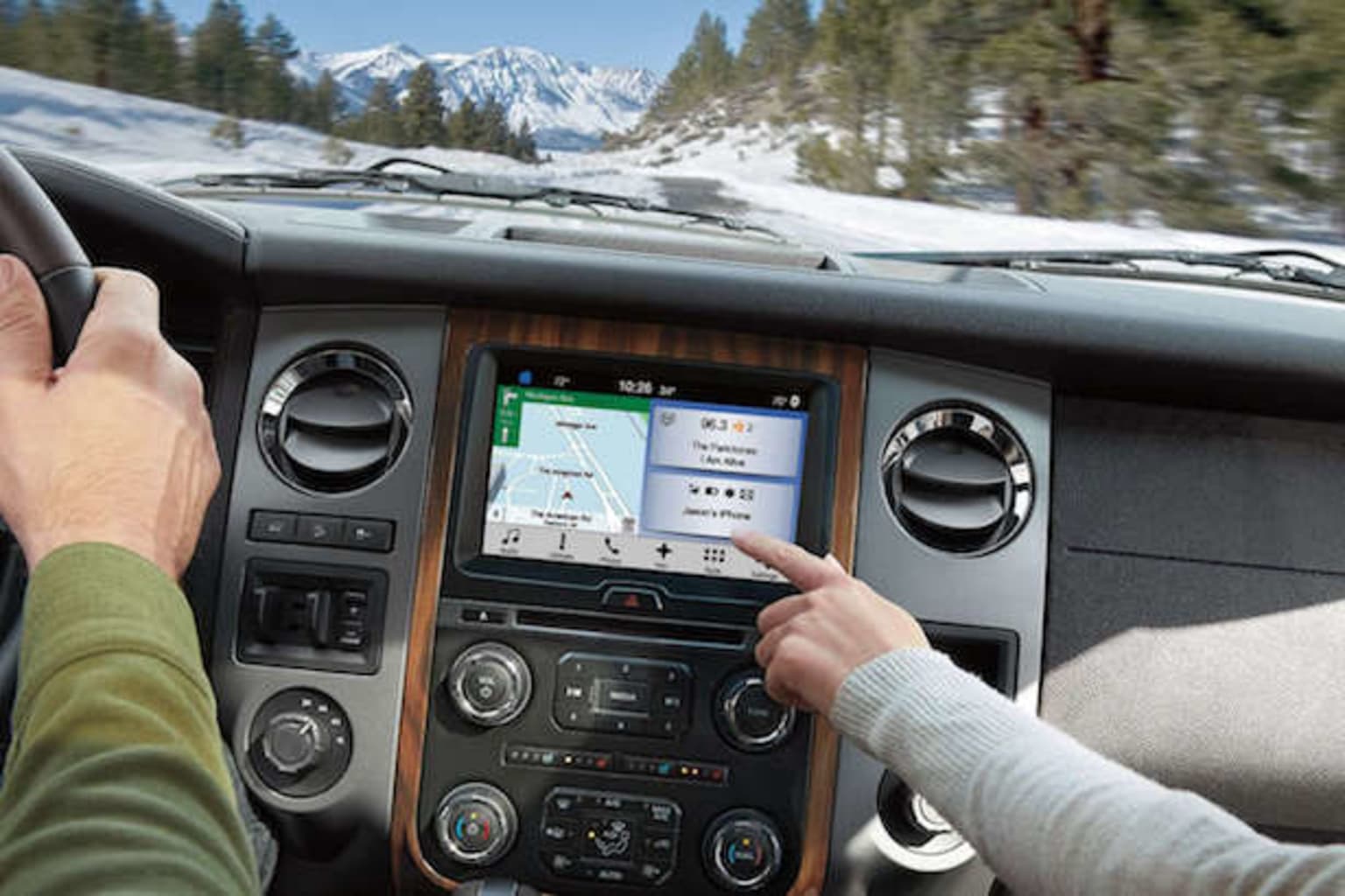 a person driving a car with a gps device in their hand and a snow covered mountain in the background