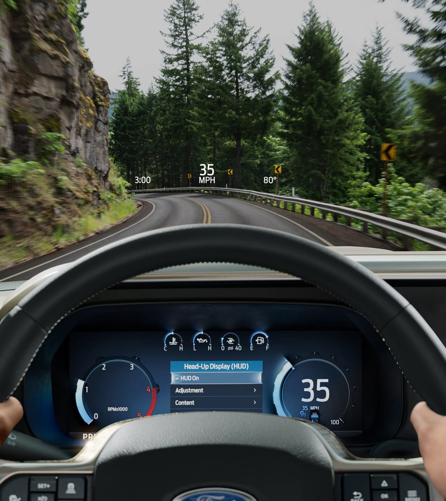 Person holding a steering wheel with digital dashboard showing speed and navigation on a scenic road through a green forest with rocky cliffs.