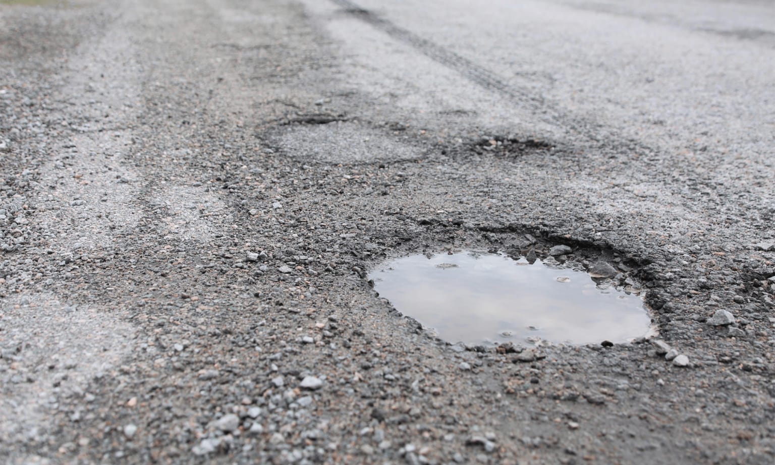 a puddle of water in the middle of a road with a tire track in the middle of the road