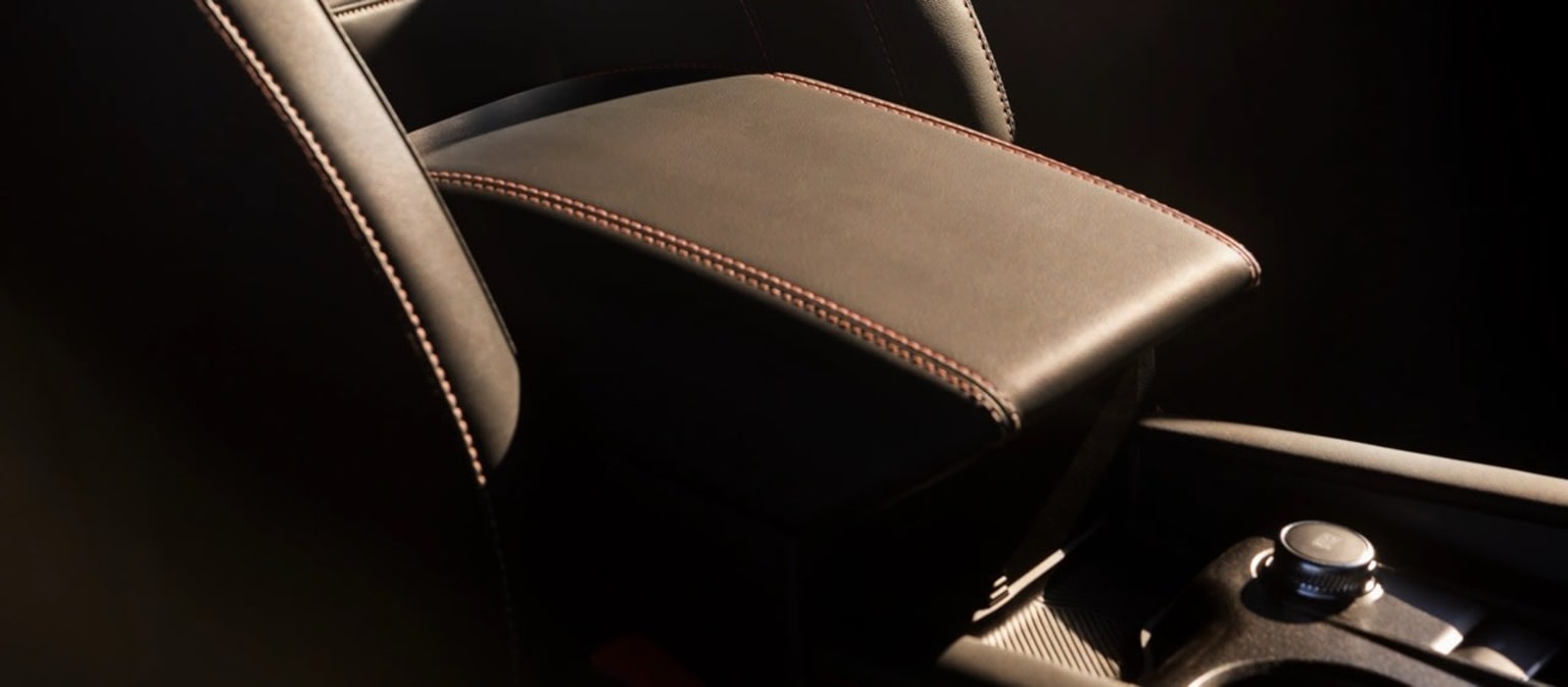 Close-up view of a leather-upholstered car seat with a center console and gear shift visible in the background.