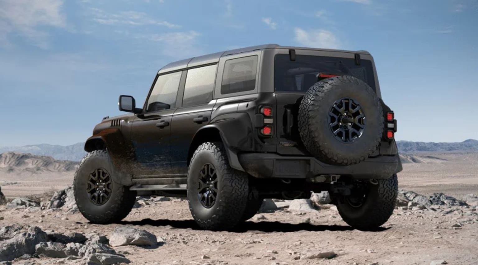 Off-road vehicle in desert landscape with rocky terrain and clear sky.