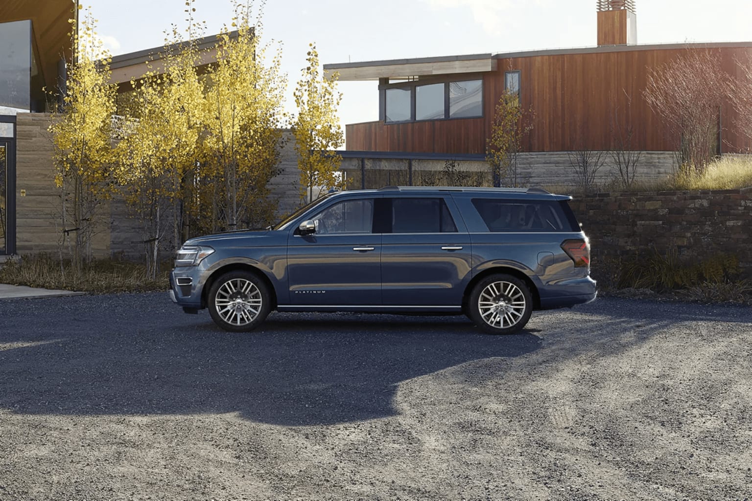 SUV parked in foreground with trees and modern building in background.