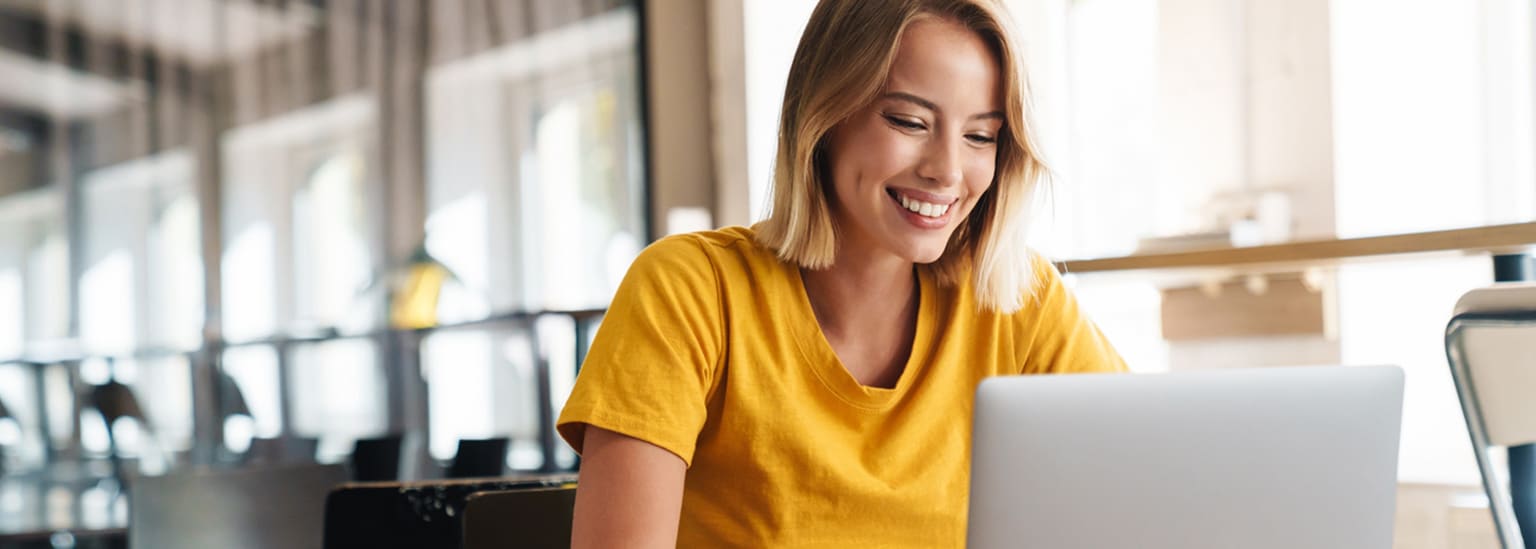 Woman working on laptop in modern cafe setting.