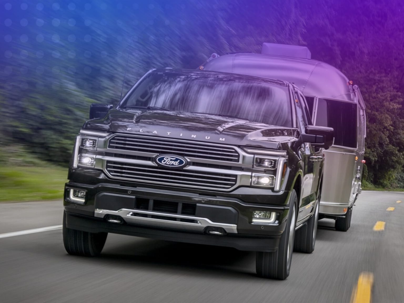 A large, powerful pickup truck is speeding down a winding road, surrounded by a blurred, lush green landscape in the background.