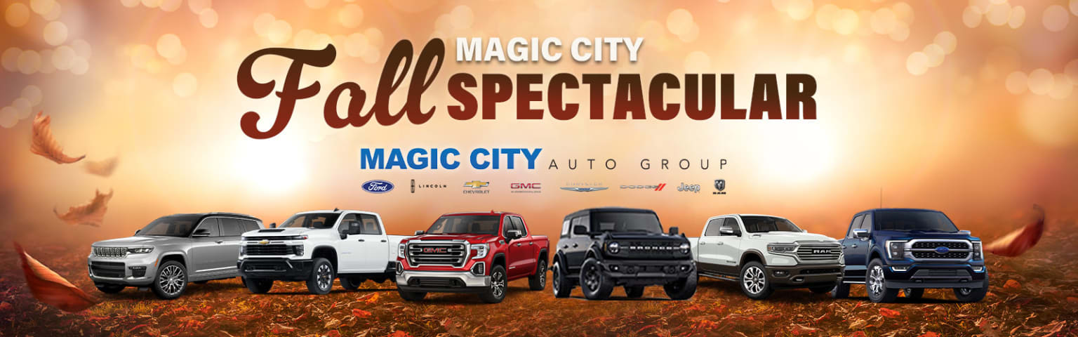 Large pickup trucks and SUVs showcased at a fall event by an auto dealership group.