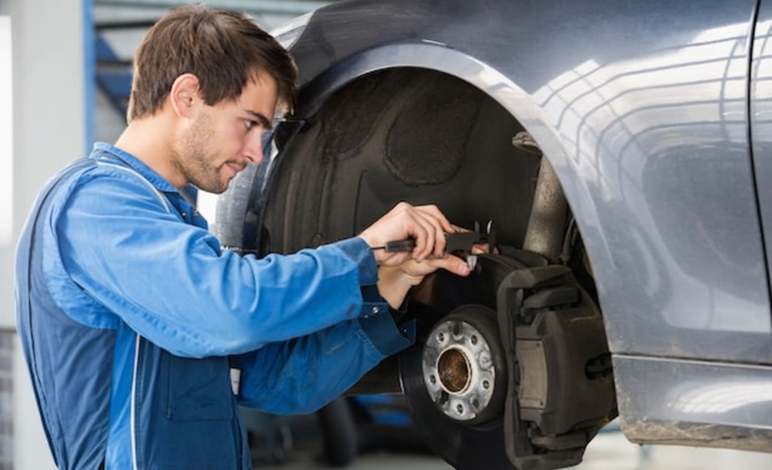 a man working on a tire on a car in a garage with a wrench in his hand and a wrench in his other hand