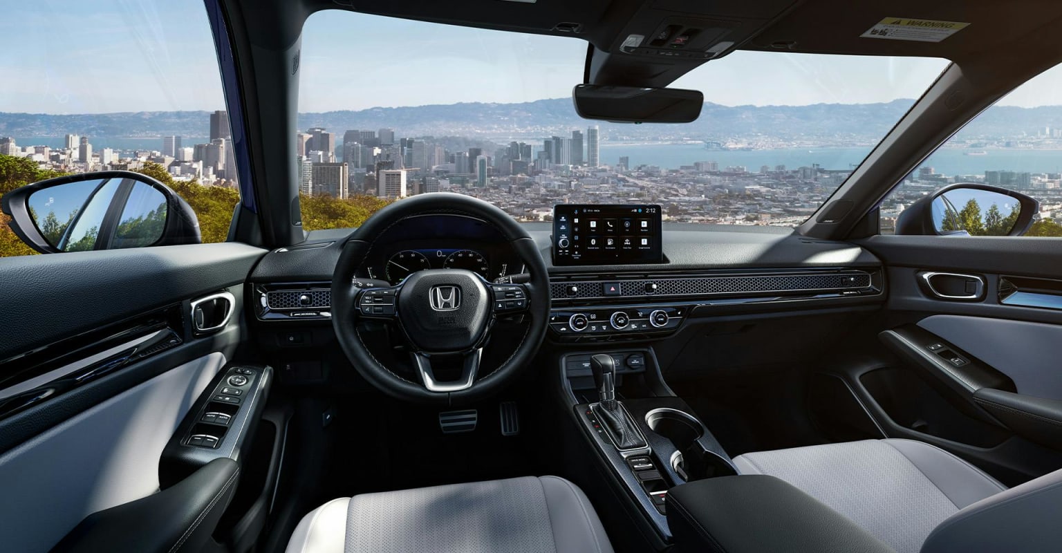 Interior of a modern car with a sleek dashboard and steering wheel against a backdrop of city skyline and ocean.