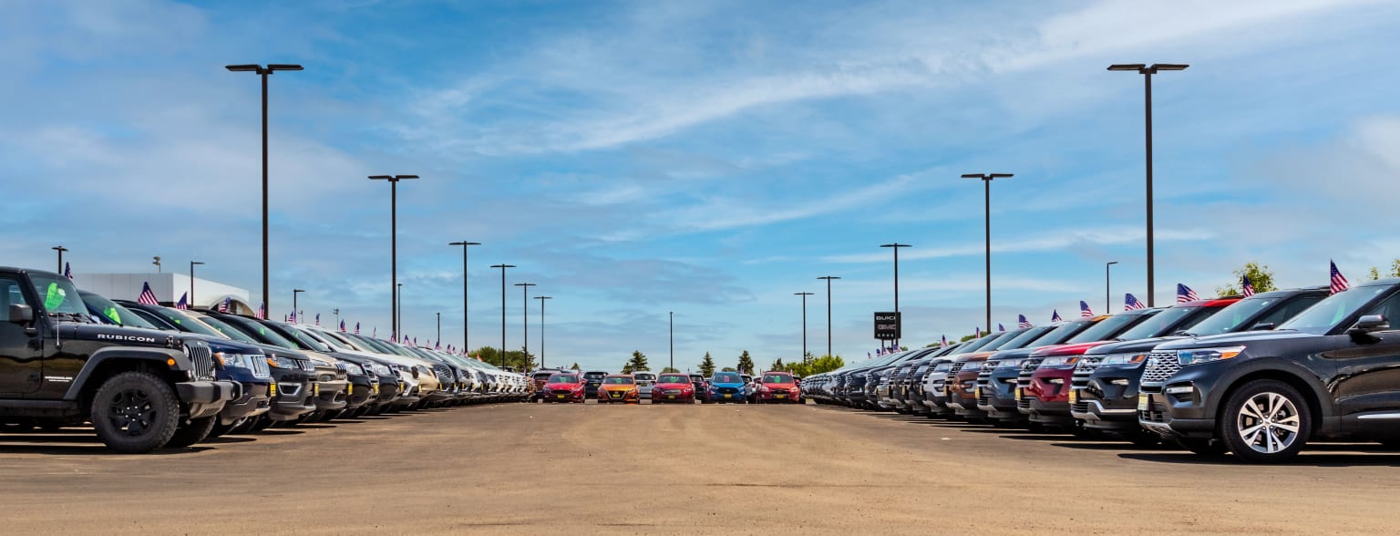 a parking lot filled with lots of cars under a blue sky with some clouds in the sky and a traffic light