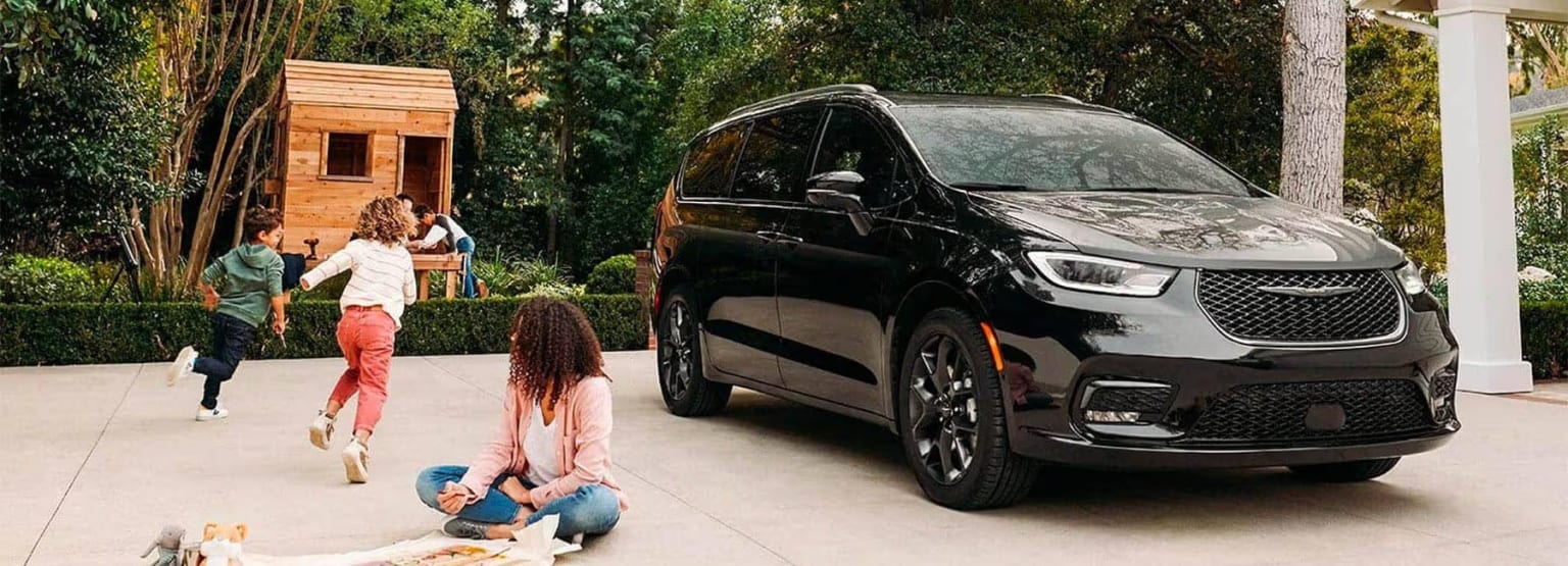 Black SUV in wooded area with woman and child interacting in foreground.