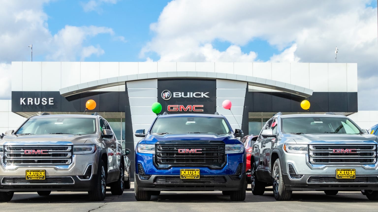 three trucks are parked in front of a building with a sign that says buick and gmc on it