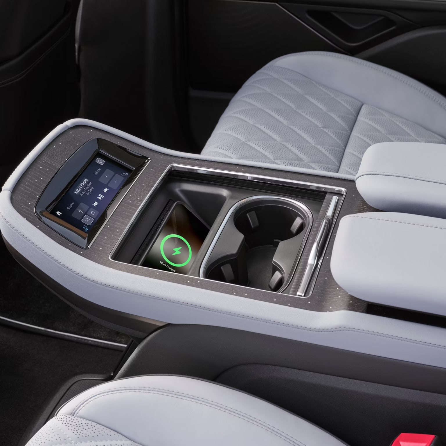 The image shows the center console of a vehicle with a display screen, various controls, and storage compartments.