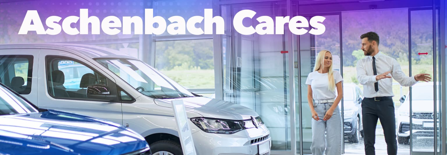 A woman smiling in front of a car dealership.