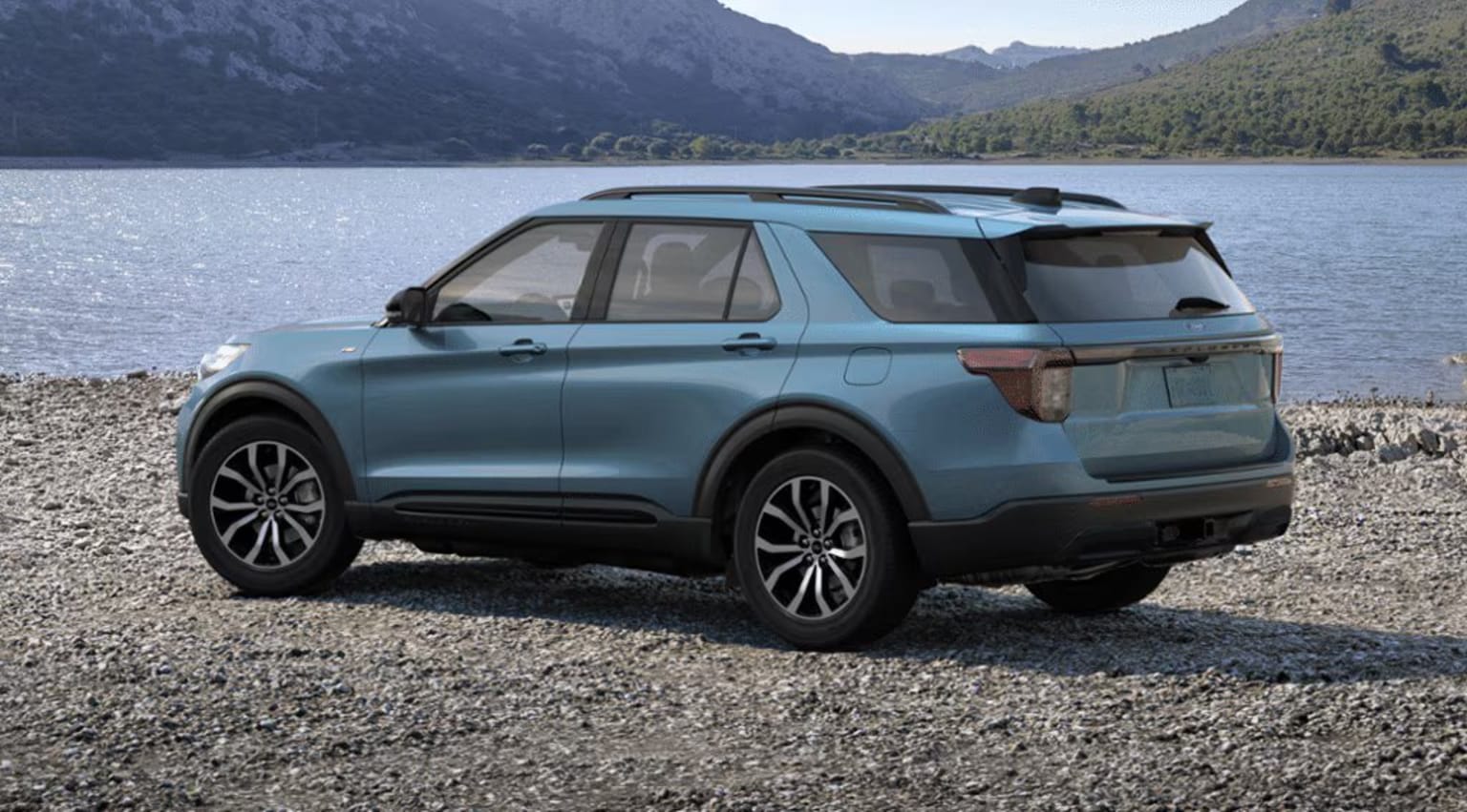 2025 Ford Explorer Exterior Color Option Vapor Blue Metallic parked on a rocky shore with a serene lake and mountains in the background.