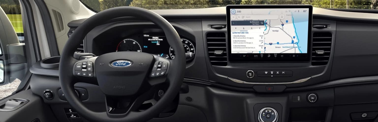 "Interior of a vehicle with a steering wheel, dashboard, and a large touchscreen display showing a navigation map."