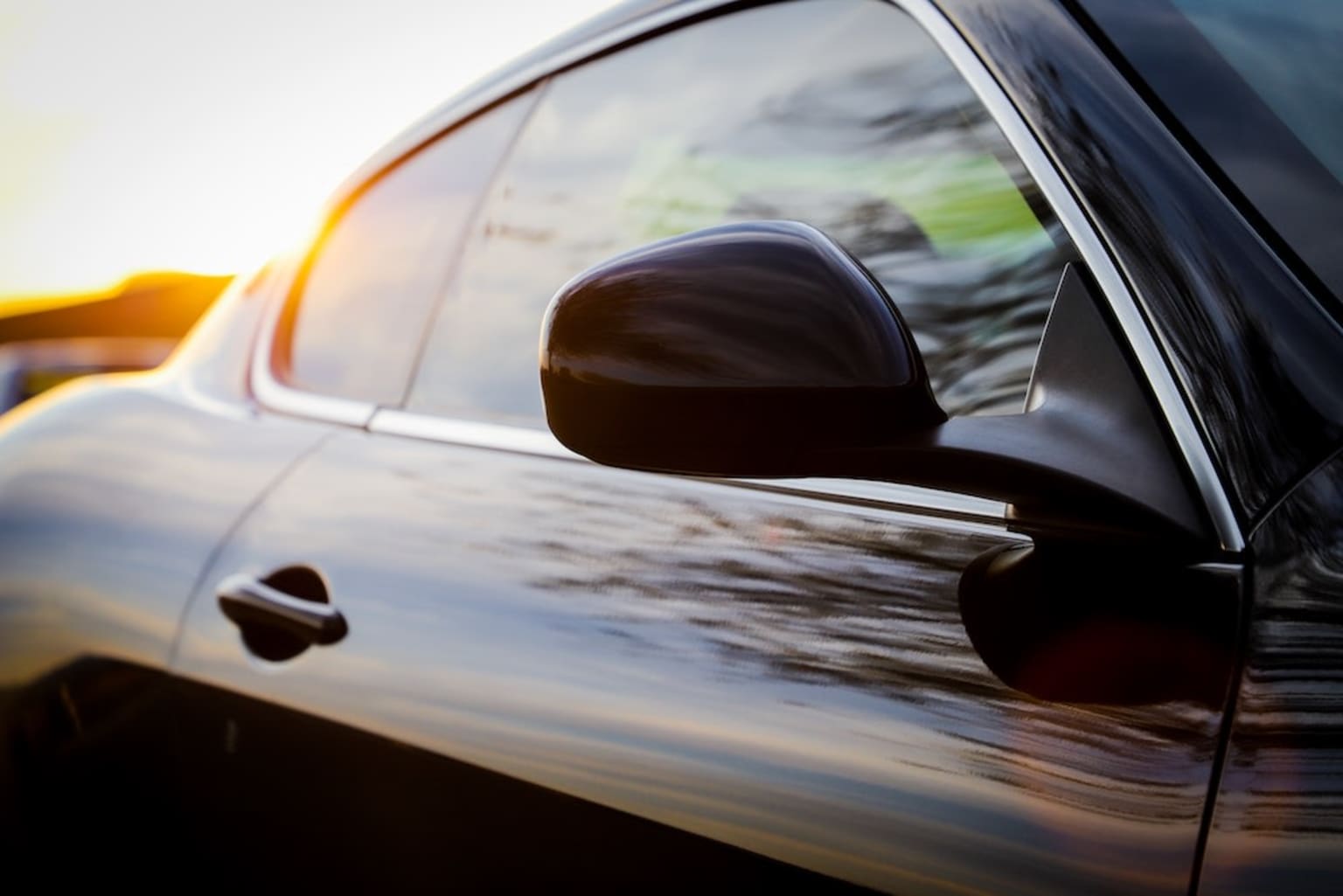 a close up of a car's side mirror with the sun shining in the back of the car