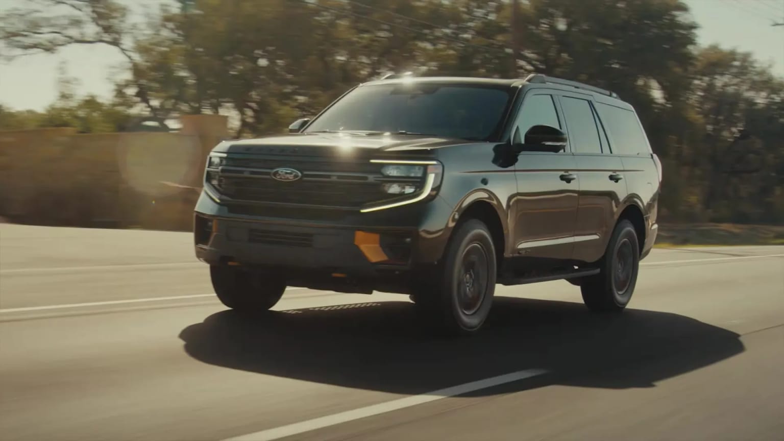 An SUV driving down a road surrounded by trees and foliage, creating a dynamic and adventurous scene.
