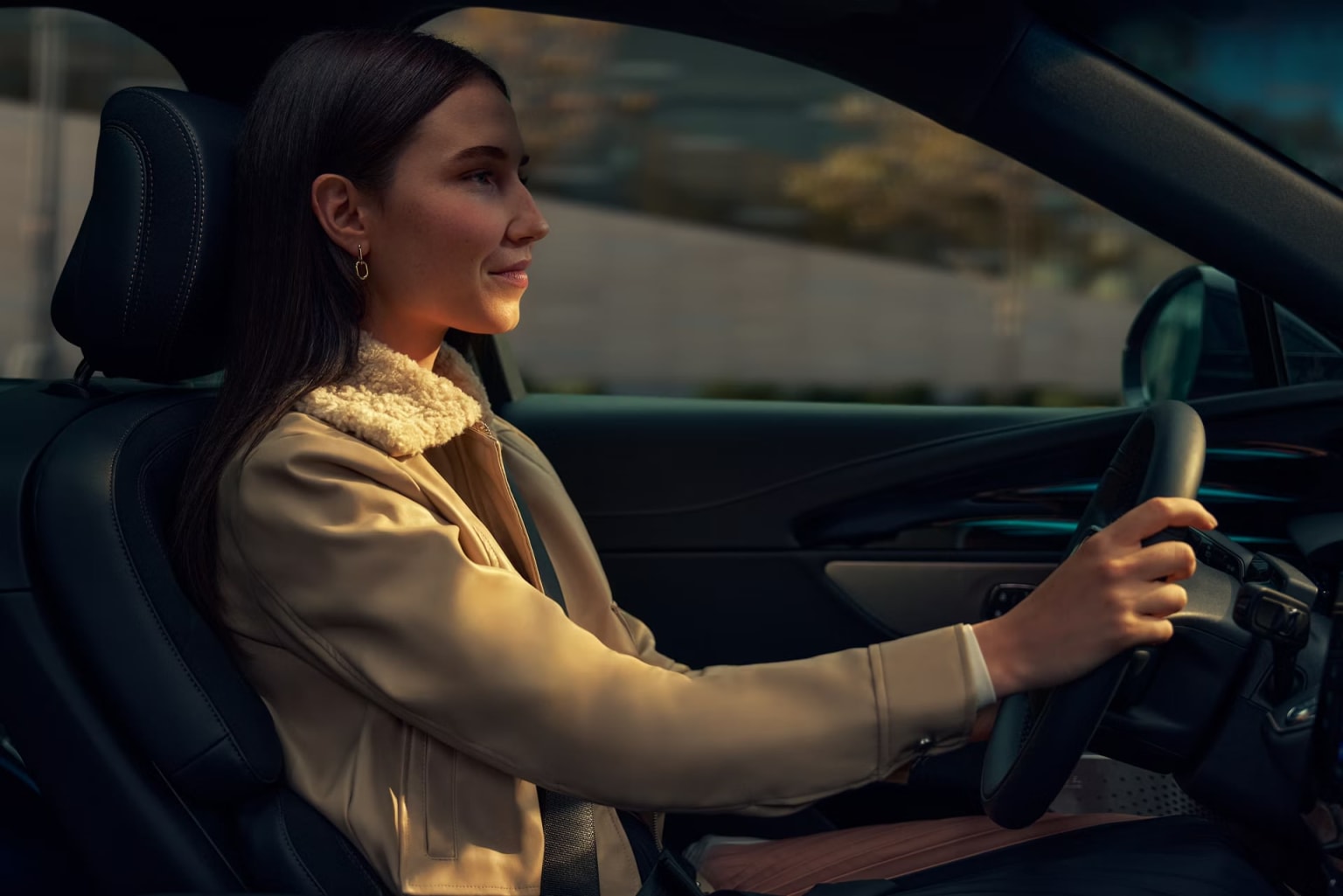 A woman driving a car with a scenic outdoor landscape in the background.