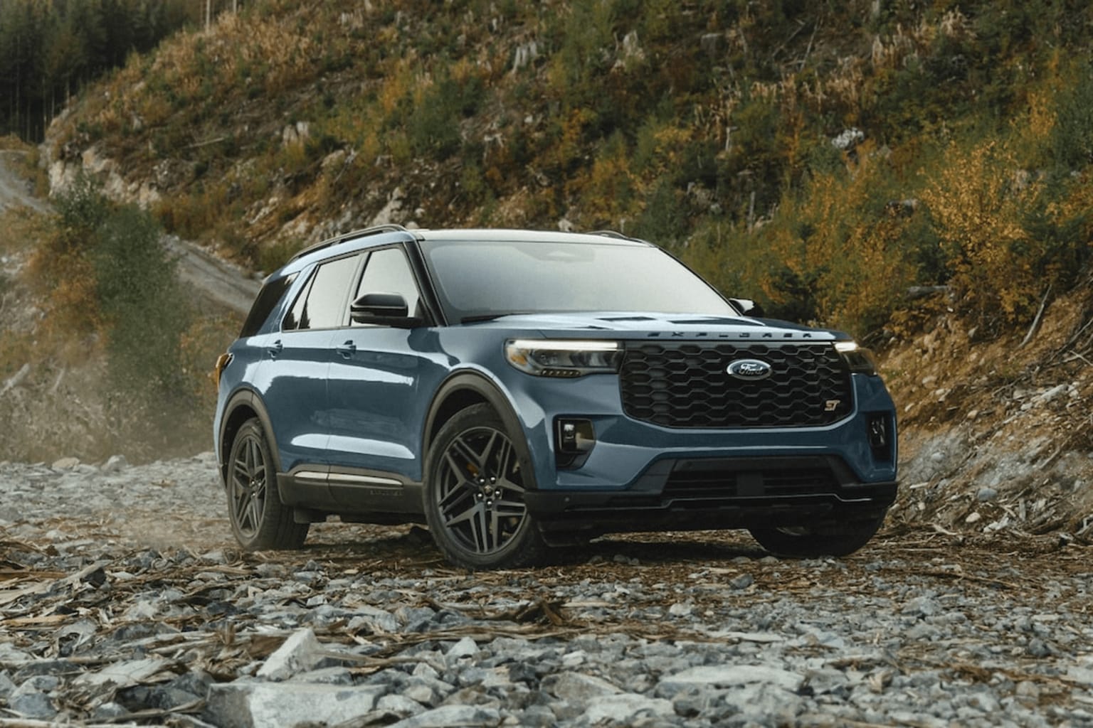 A rugged, off-road-ready SUV on rocky, mountainous terrain with lush vegetation in the background, showcasing a versatile and capable vehicle ideal for outdoor adventures.