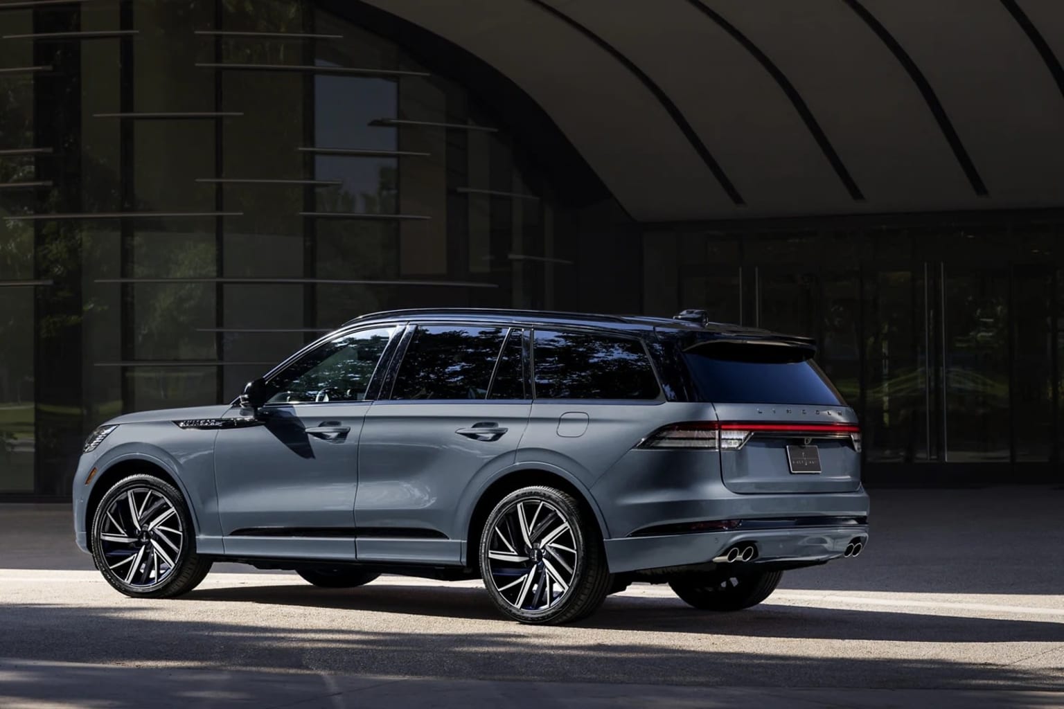 Silver SUV parked in front of modern industrial-style building with arched windows.