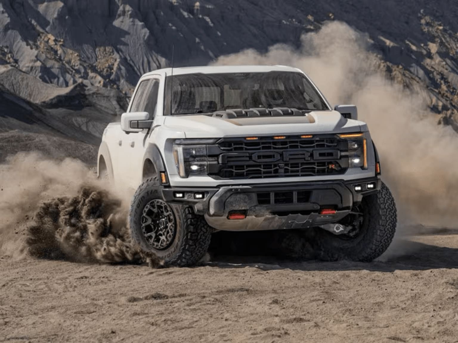 Off-road truck kicking up dust on rugged mountain terrain