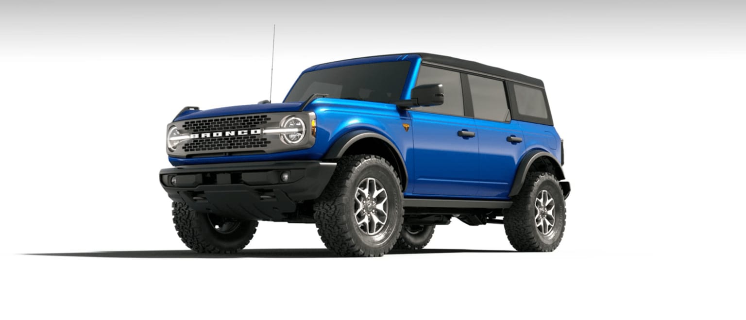 A rugged off-road vehicle with large tires and a boxy, angular design in blue color set against a plain, light-colored background.