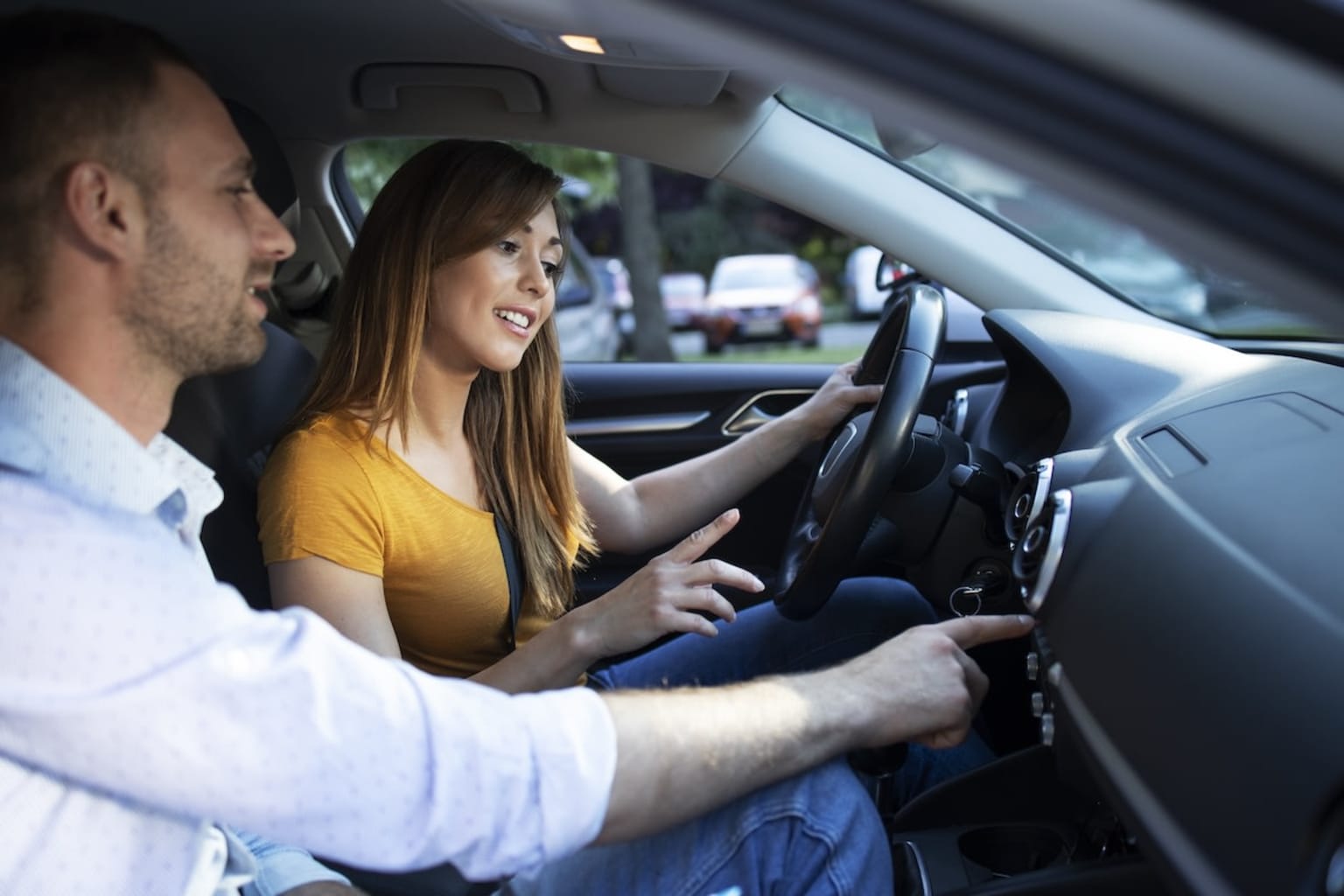 a man and a woman are sitting in a car and one is holding the steering wheel and the other is holding the steering wheel