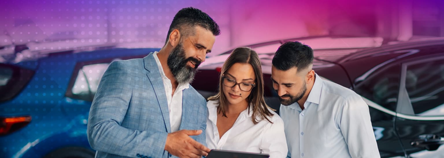 A professional car salesman communicating with customers using a tablet, with cars in the background.