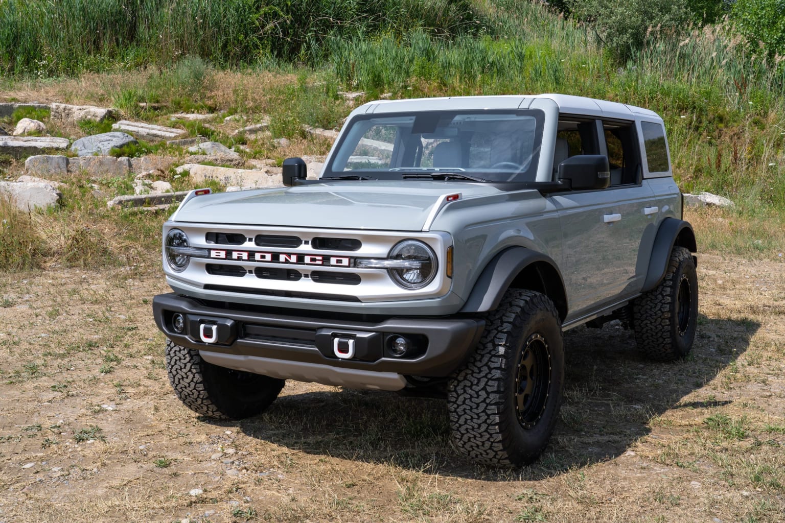 a silver truck parked on top of a dry grass covered field next to a field with rocks and grass