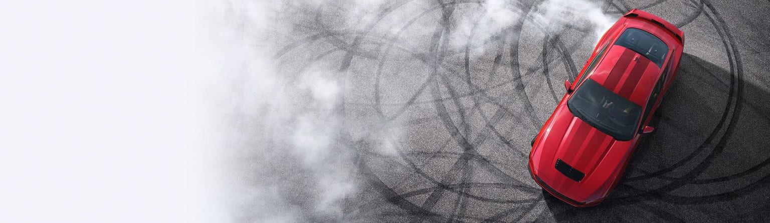 A red sports car is partially visible in the foreground, surrounded by a hazy, abstract background of swirling gray lines and shapes.