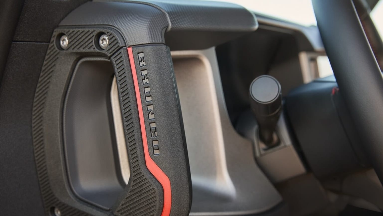 Interior view of a vehicle showing a carbon fiber-style panel with various controls and buttons.
