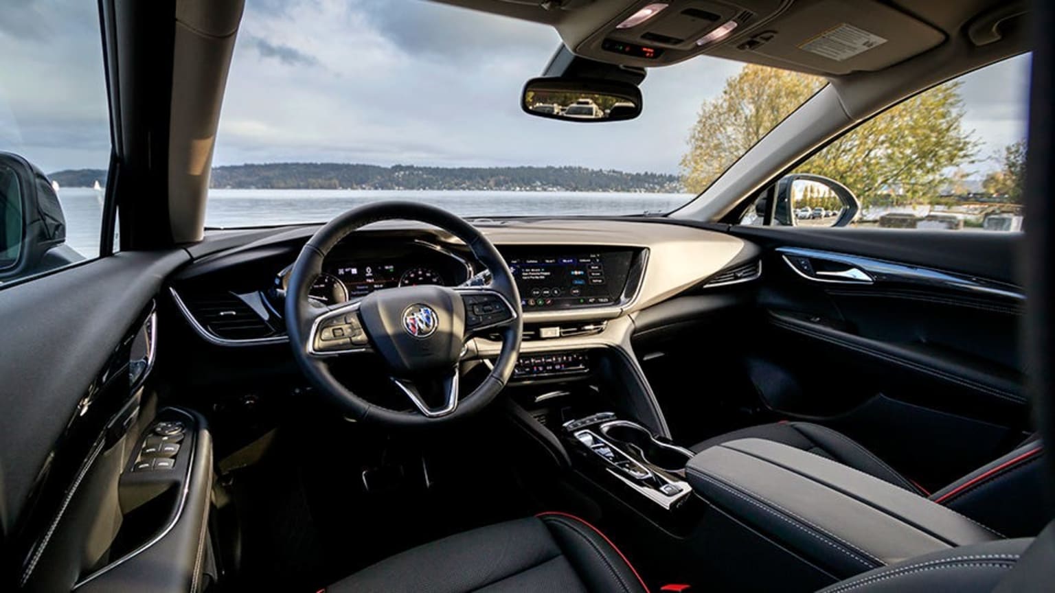the interior of a car with a view of a lake and mountains in the distance from the driver's seat
