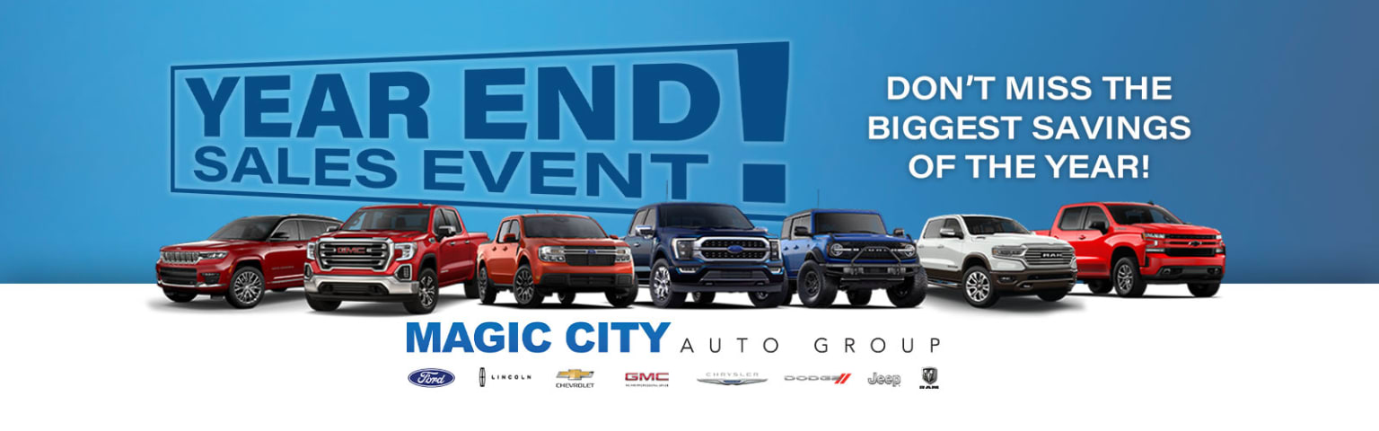 The image displays a variety of pickup trucks from different automotive brands prominently featured in the foreground against a blue sky background. The text above the vehicles advertises a "Year End Sales Event" hosted by a local auto group.