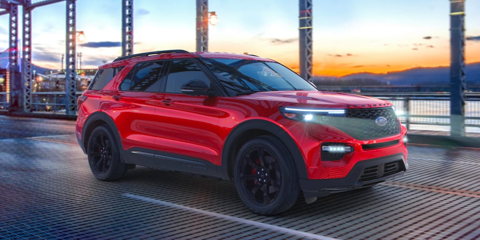 a red suv driving on a bridge at night with the sun setting in the background and a bridge in the foreground