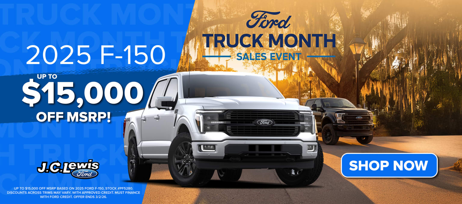 A truck displayed in the foreground with a promotional banner for a sales event in the background, showcasing a scenic landscape with a sunset.