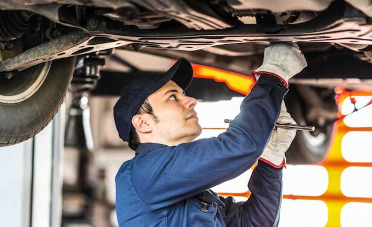 a man working on a car under the hood of a vehicle with a wrench in his hand and a wrench in his other hand