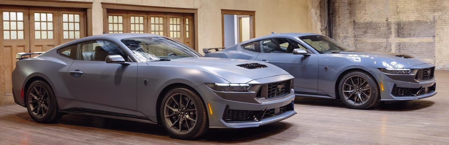 Two high-performance sports cars parked in a garage or showroom setting with wooden doors and walls.