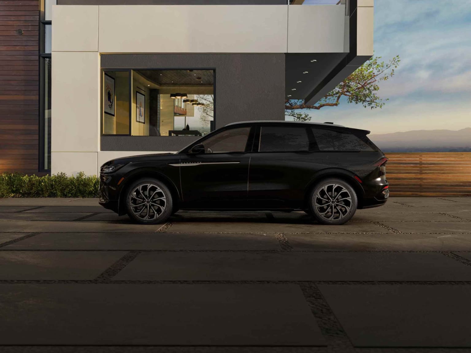 A sleek, black SUV parked in front of a modern, minimalist building with large windows, surrounded by lush greenery.