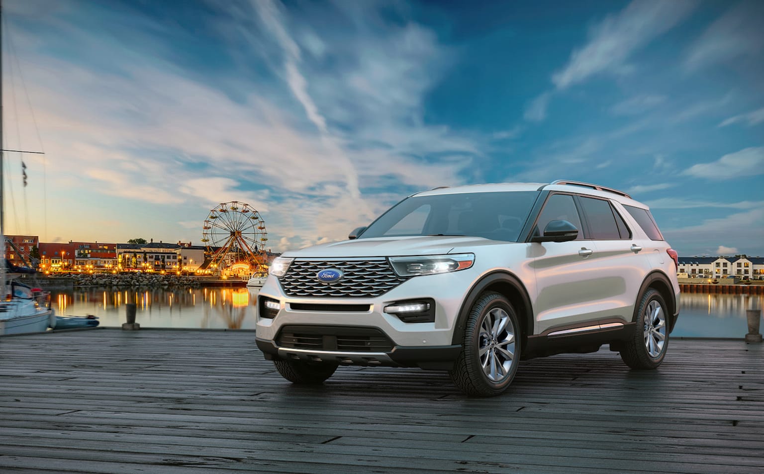 a white ford explorer is parked on a dock near a ferris wheel and a ferris wheel in the background