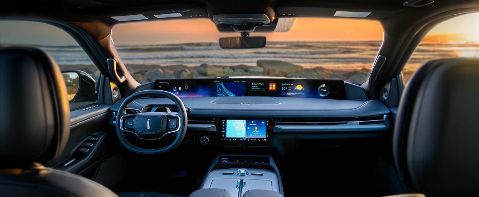Interior view of a vehicle with a dashboard display showing a scenic ocean view.